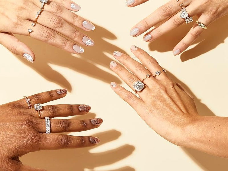 Hands with different engagement rings showcasing how various ring styles, including wider bands and larger stones, complement different finger shapes and sizes for the perfect engagement ring.